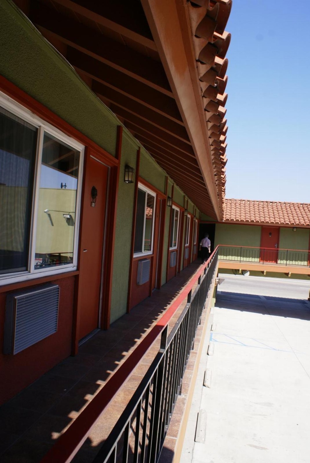 A green and red building with a balcony and a tiled roof